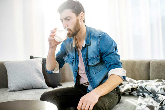 Man drinking water on the couch after getting too high from thc weed